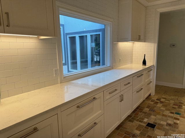 kitchen with backsplash, white cabinetry, light stone countertops, and plenty of natural light