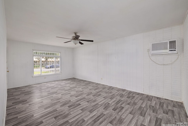 unfurnished room with a wall mounted air conditioner, hardwood / wood-style floors, and ceiling fan