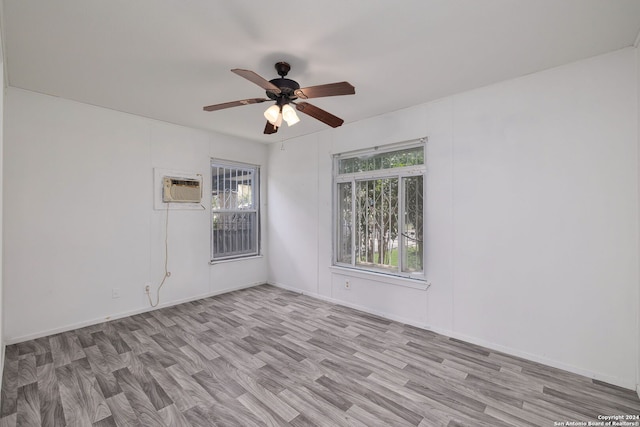 empty room with an AC wall unit, ceiling fan, and light hardwood / wood-style floors