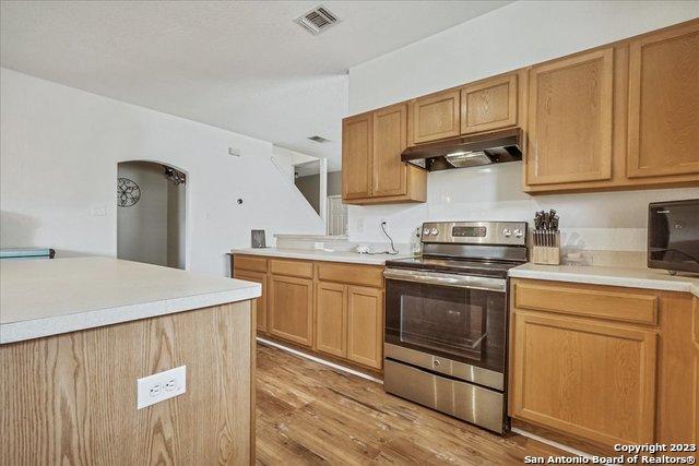 kitchen featuring stainless steel electric stove and light hardwood / wood-style floors