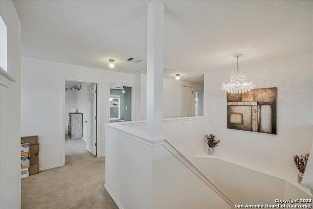 corridor featuring light carpet and an inviting chandelier