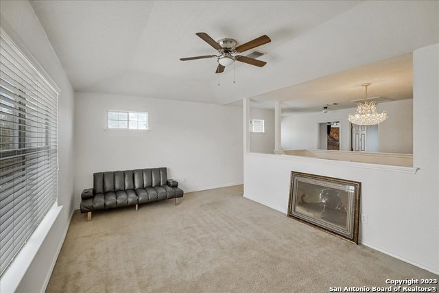 unfurnished living room with carpet and ceiling fan with notable chandelier