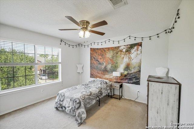 bedroom with ceiling fan, carpet floors, and a textured ceiling