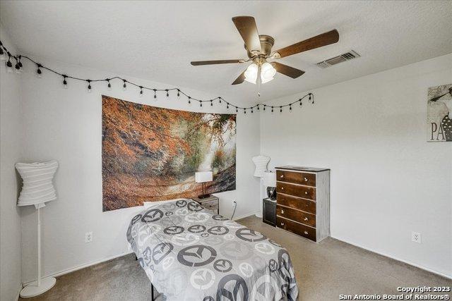 bedroom with ceiling fan, carpet floors, and a textured ceiling