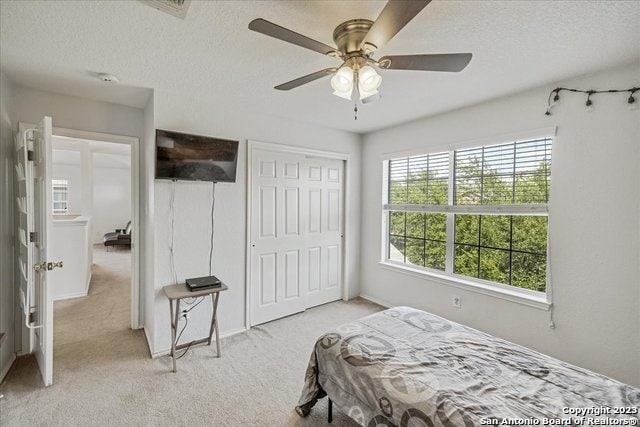 bedroom with light carpet, a textured ceiling, a closet, and ceiling fan