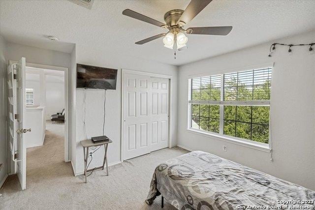 carpeted bedroom featuring ceiling fan, a closet, and a textured ceiling