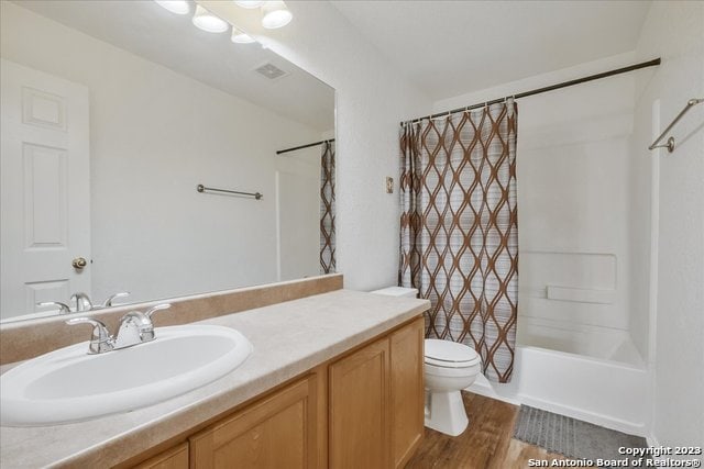 full bathroom featuring vanity, hardwood / wood-style flooring, toilet, and shower / bath combination with curtain