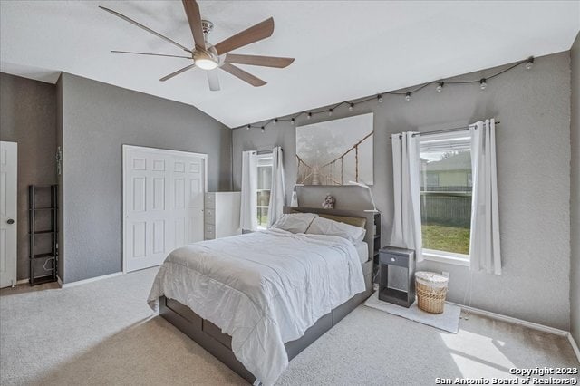 bedroom featuring light carpet, vaulted ceiling, a closet, and ceiling fan