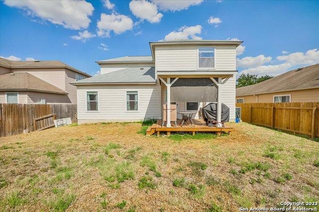 back of house featuring a wooden deck and a lawn