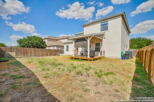 back of house featuring a wooden deck, a lawn, and central air condition unit