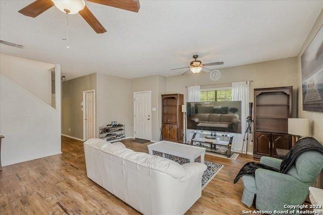 living room with light hardwood / wood-style flooring and ceiling fan