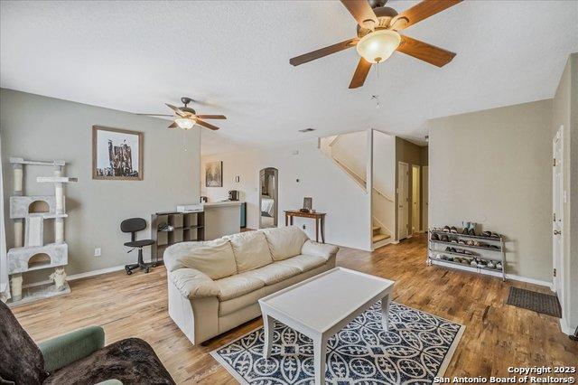 living room featuring ceiling fan, a textured ceiling, and light wood-type flooring