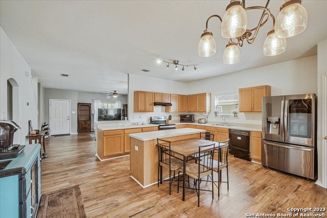 kitchen featuring a center island, ceiling fan, stainless steel appliances, light hardwood / wood-style floors, and decorative light fixtures