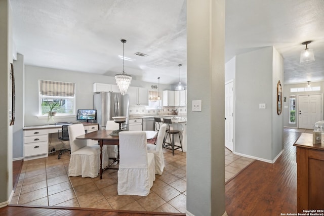 dining space featuring baseboards, visible vents, a chandelier, and tile patterned floors