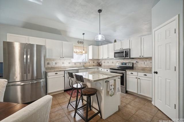 kitchen featuring a breakfast bar area, a sink, a kitchen island, hanging light fixtures, and appliances with stainless steel finishes