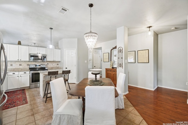 dining space featuring a chandelier, visible vents, baseboards, and light tile patterned floors