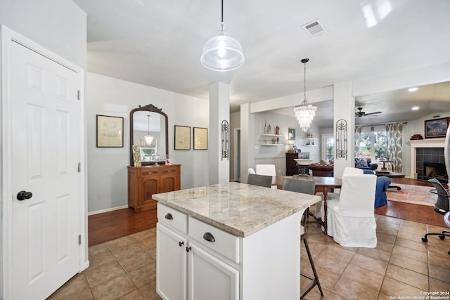 kitchen featuring a center island, pendant lighting, visible vents, open floor plan, and white cabinetry