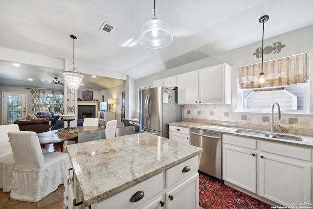 kitchen with white cabinets, a kitchen island, appliances with stainless steel finishes, open floor plan, and a sink