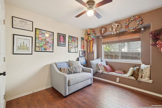 living area featuring baseboards, dark wood finished floors, and a ceiling fan