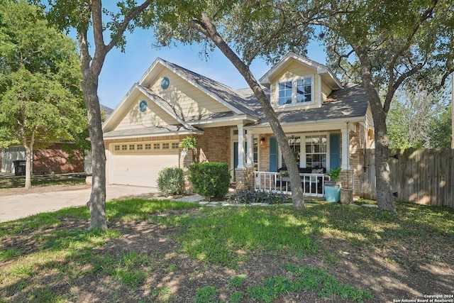 craftsman inspired home featuring brick siding, covered porch, concrete driveway, fence, and a garage