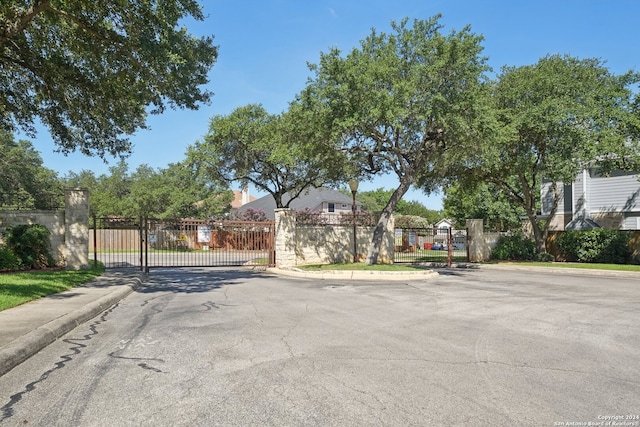 view of street featuring sidewalks, a gate, a gated entry, and curbs