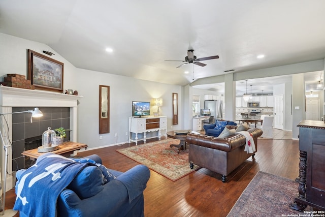 living room featuring lofted ceiling, visible vents, dark wood finished floors, and a tiled fireplace