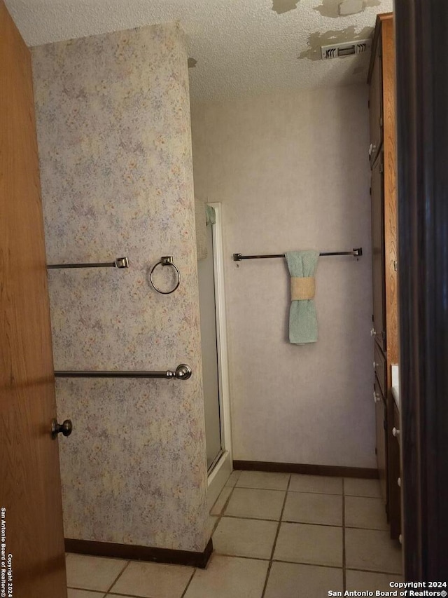 bathroom featuring tile patterned flooring, walk in shower, and a textured ceiling