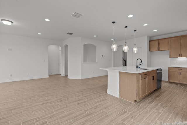 kitchen featuring sink, tasteful backsplash, hanging light fixtures, stainless steel dishwasher, and an island with sink