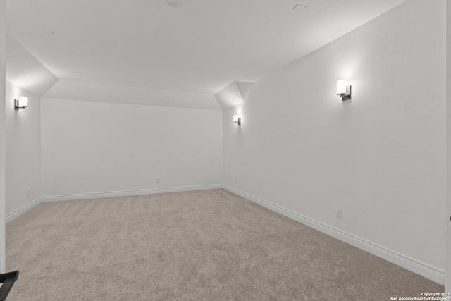 carpeted spare room featuring vaulted ceiling