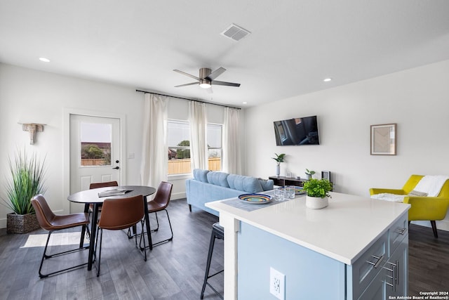 kitchen with ceiling fan, a kitchen island, dark hardwood / wood-style floors, and a breakfast bar