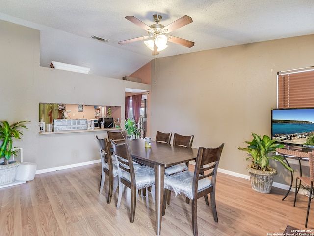 dining space featuring high vaulted ceiling, light wood-type flooring, ceiling fan, and a textured ceiling