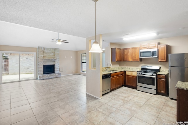 kitchen featuring appliances with stainless steel finishes, a fireplace, sink, hanging light fixtures, and light tile patterned floors