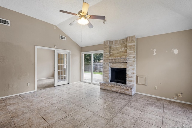 unfurnished living room with lofted ceiling, light tile patterned floors, ceiling fan, and a brick fireplace