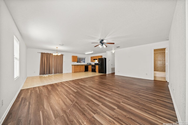 unfurnished living room with ceiling fan with notable chandelier and tile patterned floors