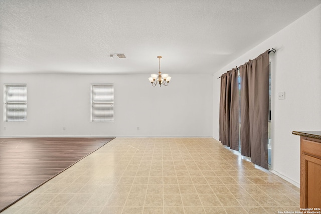 empty room featuring a notable chandelier and a textured ceiling