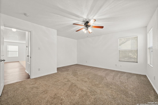 carpeted spare room featuring ceiling fan and a textured ceiling