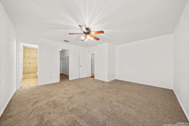 unfurnished bedroom featuring ceiling fan, carpet, connected bathroom, a spacious closet, and a closet