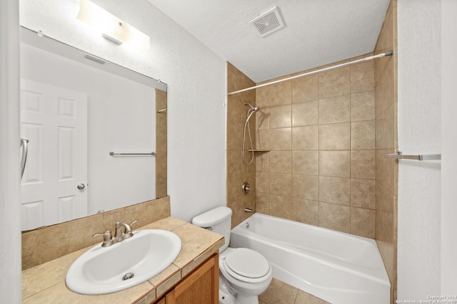 full bathroom featuring tiled shower / bath, tile patterned flooring, vanity, toilet, and a textured ceiling