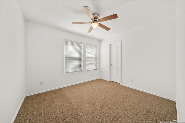 empty room featuring ceiling fan and carpet