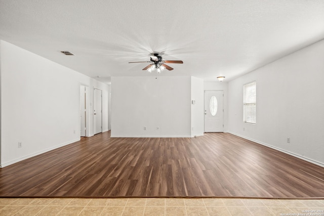 unfurnished living room with ceiling fan, hardwood / wood-style floors, and a textured ceiling