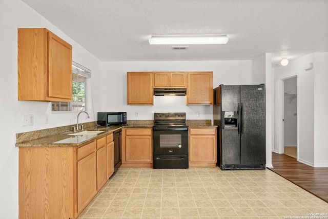 kitchen featuring sink, dark stone countertops, a textured ceiling, and black appliances