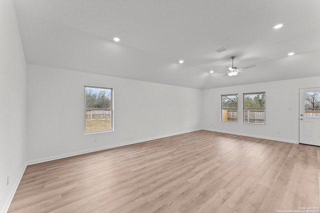 empty room with ceiling fan, vaulted ceiling, and light hardwood / wood-style floors