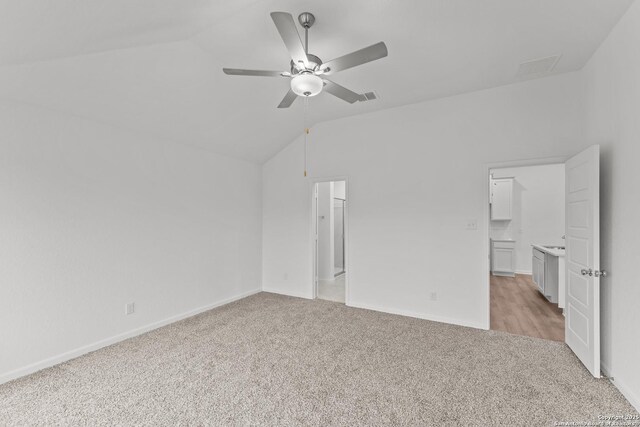 interior space featuring ceiling fan, light colored carpet, and lofted ceiling