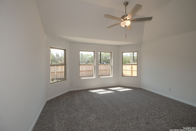 spare room featuring ceiling fan, dark carpet, and vaulted ceiling