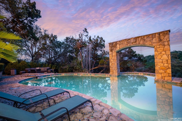 pool at dusk featuring an outdoor hangout area and a patio area