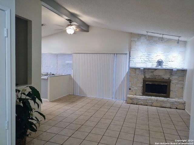 interior space with ceiling fan, lofted ceiling with beams, a textured ceiling, and a fireplace