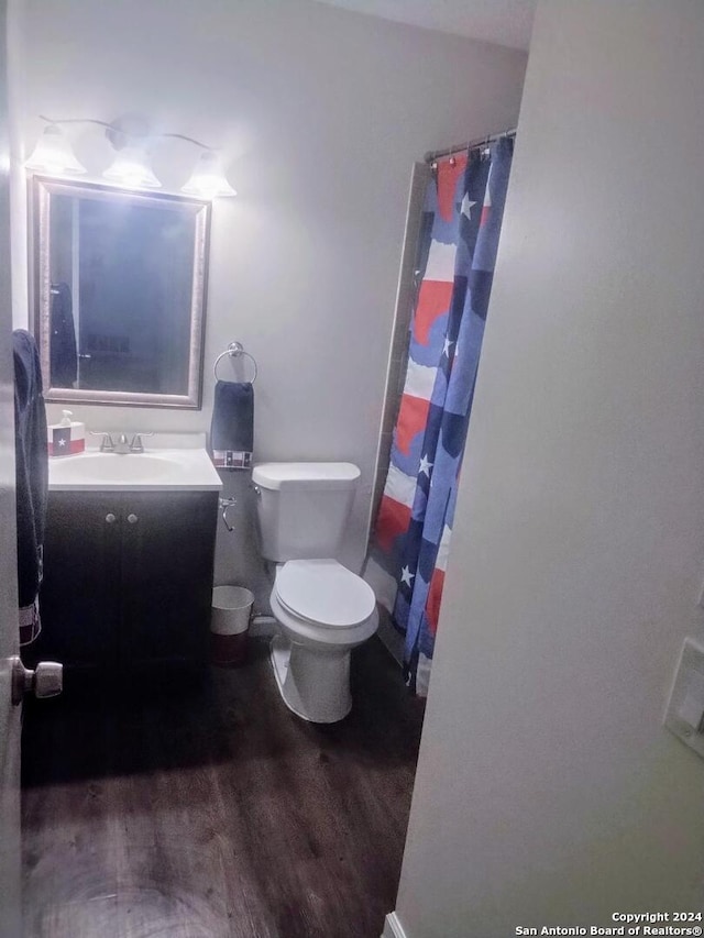 bathroom with wood-type flooring, vanity, toilet, and walk in shower