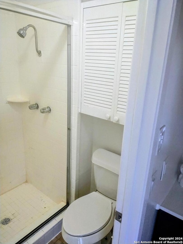 bathroom featuring toilet and a shower with door