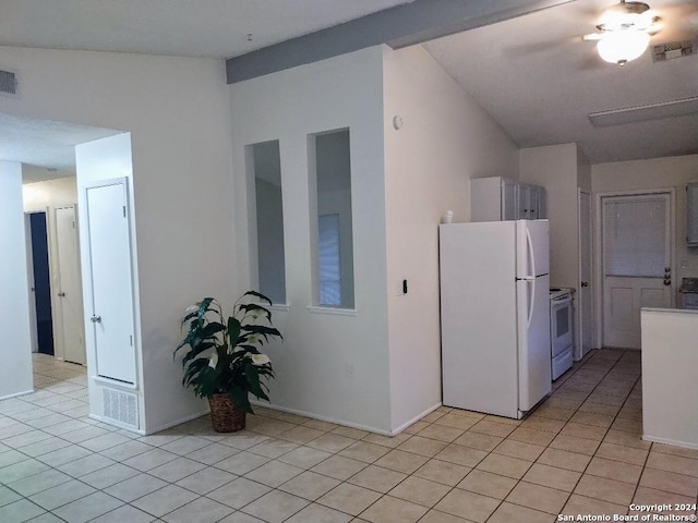 kitchen with white appliances, vaulted ceiling, and light tile patterned floors