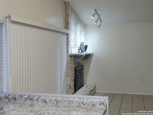 room details with a textured ceiling, a stone fireplace, and track lighting